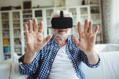 Senior man wearing virtual reality headset in living room