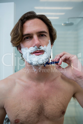 Man using a razor to shave his beard off