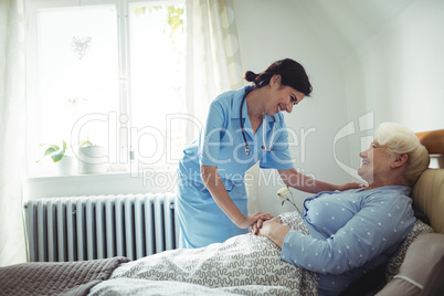Nurse interacting with senior woman on bed