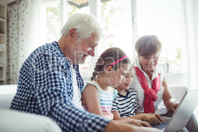 Grandchildren using laptop with their grandparents