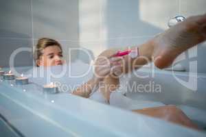 Woman using razor while having bath in bath tub