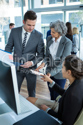 Businesspeople discussing at table over digital tablet