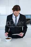 Businessman reading newspaper while having breakfast in kitchen