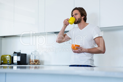 Man drinking coffee while having breakfast in kitchen