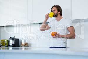 Man drinking coffee while having breakfast in kitchen