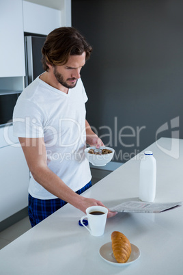 Man reading newspaper while having breakfast in kitchen
