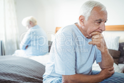 Sad senior couple sitting on bed