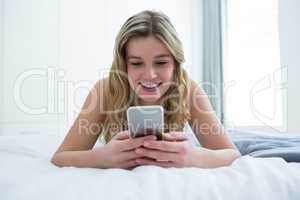 Woman lying on bed and using mobile phone on bed