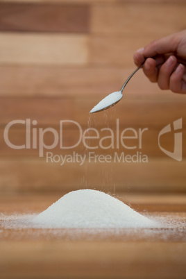 Woman hand pouring sugar from spoon
