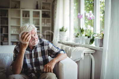 Tensed senior man sitting on sofa