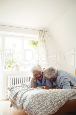 Senior couple interacting while relaxing on bed