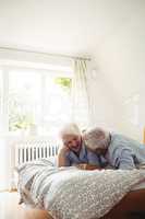 Senior couple interacting while relaxing on bed