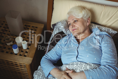 Worried senior woman relaxing on bed