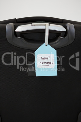 Travel insurance label tied to a suitcase
