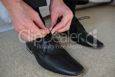 Man tying a shoelaces in bedroom