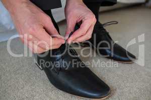 Man tying a shoelaces in bedroom