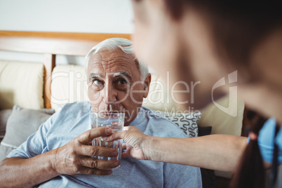 Nurse giving a glass of water to senior man