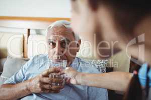 Nurse giving a glass of water to senior man