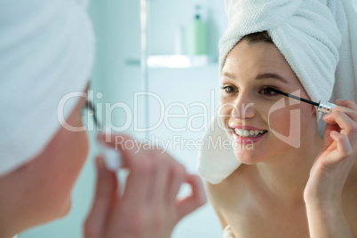 Woman applying mascara on eyelashes in bathroom