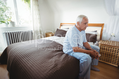 Senior man sitting on bed