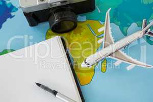 Digital camera, dairy, pen, and airplane model on table