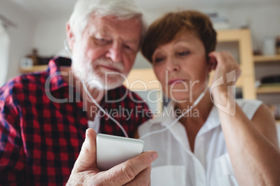 Senior couple listening to music on smartphone