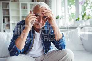 Tensed senior man talking on mobile phone