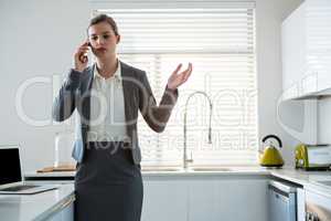 Woman talking on mobile phone in kitchen