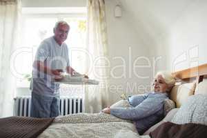Senior man serving breakfast to senior woman
