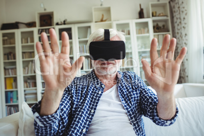 Senior man wearing virtual reality headset in living room
