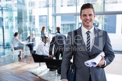 Smiling businessman standing with document in office