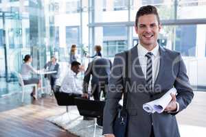 Smiling businessman standing with document in office