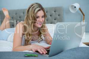 Woman using laptop on bed in bedroom