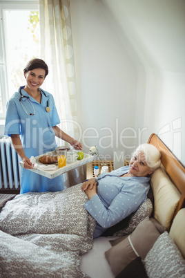 Nurse serving breakfast to senior woman