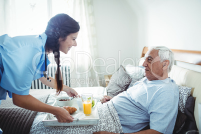 Nurse serving breakfast to senior man