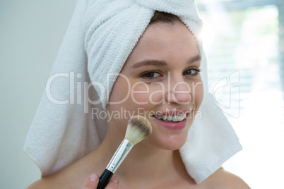 Woman applying make-up on her face in bathroom