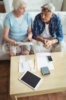 Senior couple interacting while checking the bills