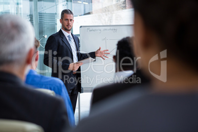 Businessman discussing on white board with co-workers