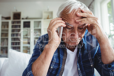 Tensed senior man talking on mobile phone