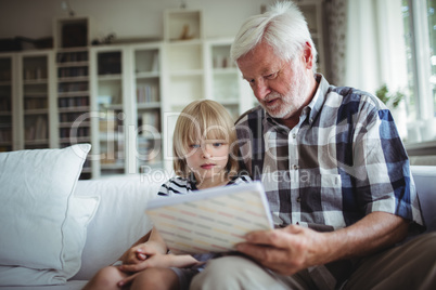 Senior man and her granddaughter looking at a photo album