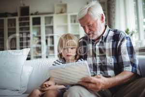 Senior man and her granddaughter looking at a photo album