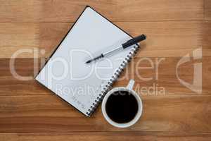 Close-up of coffee cup with diary and pen