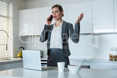 Woman talking on mobile phone in kitchen