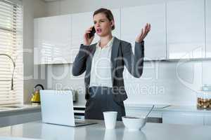 Woman talking on mobile phone in kitchen