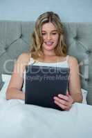 Woman using digital tablet on bed