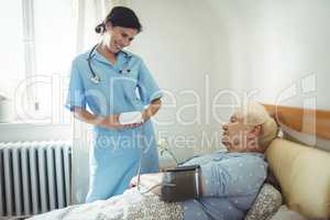 Nurse checking blood pressure of senior woman