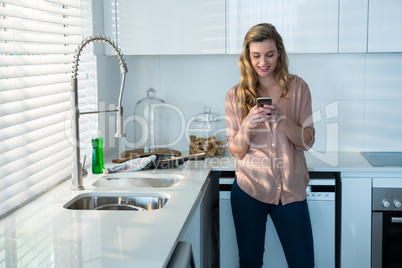 Woman using mobile phone in kitchen