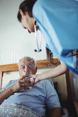 Nurse giving a glass of water to senior man