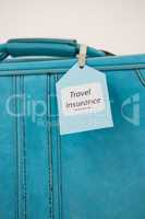 Travel insurance label tied to a suitcase