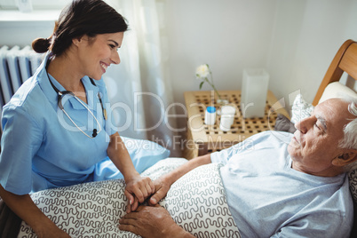 Nurse holding hands of senior man